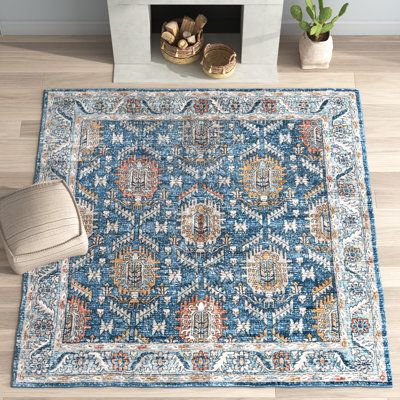 a blue rug with an ornate design on the floor in front of a fire place