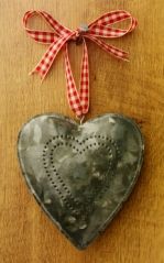 a metal heart hanging from a red and white checkered ribbon on a wooden table