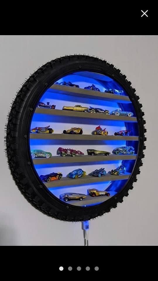 there are many toy cars on the shelf in the circle shaped display case that is lit up with blue light