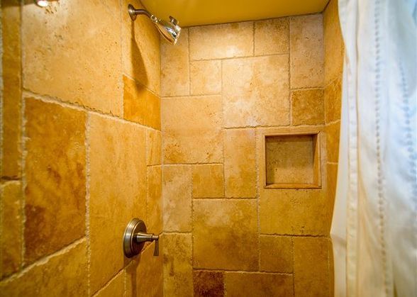 a bathroom with a shower head and tiled walls in the shower stall is seen here