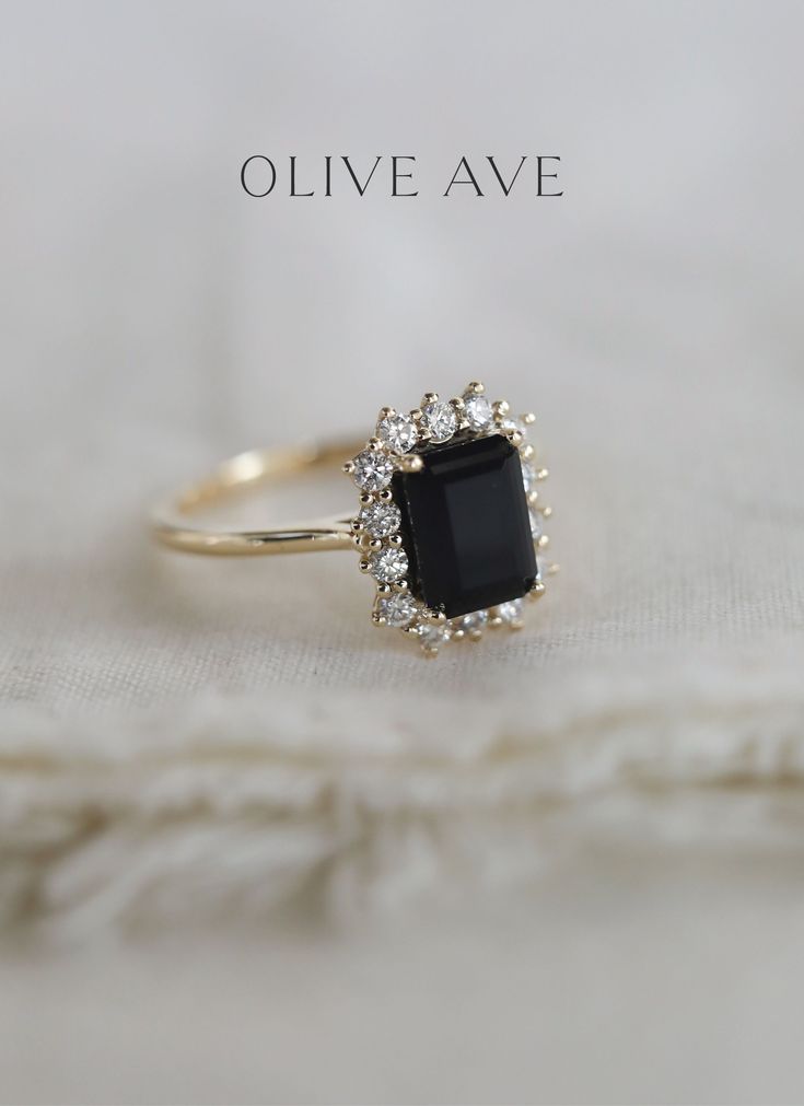 an engagement ring with a black stone surrounded by small white diamonds on a white cloth