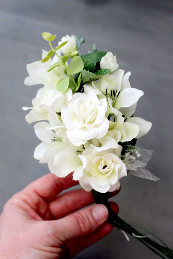 a hand holding a bouquet of white flowers