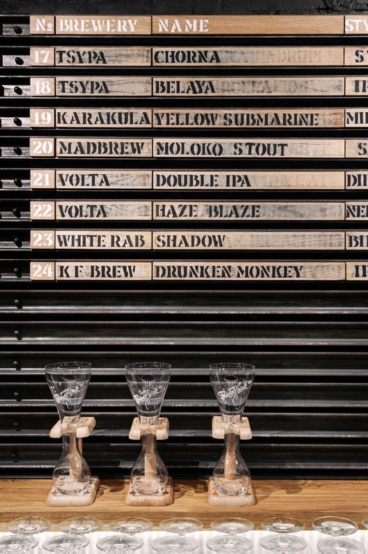 three wine glasses sitting on top of a wooden table next to a wall with names