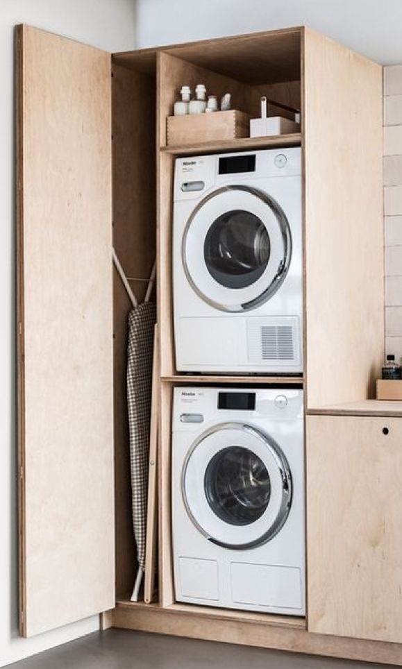 a washer and dryer in a wooden cabinet next to each other on the floor