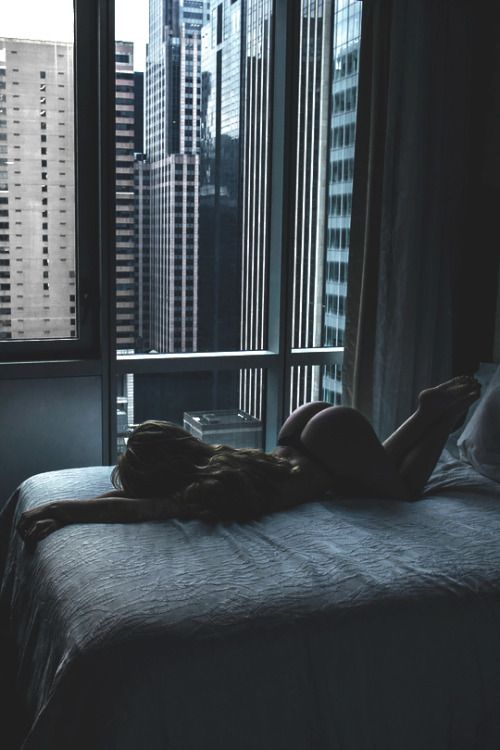 a woman laying on top of a bed in a bedroom next to a large window