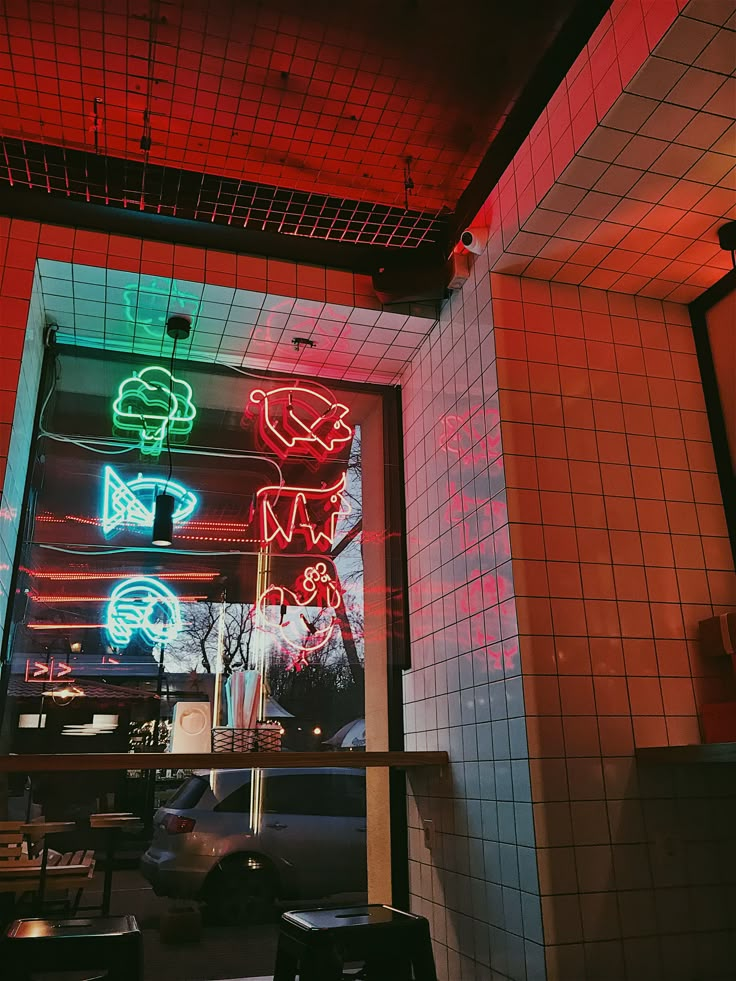 neon signs are lit up in the window of a restaurant with tiled walls and flooring