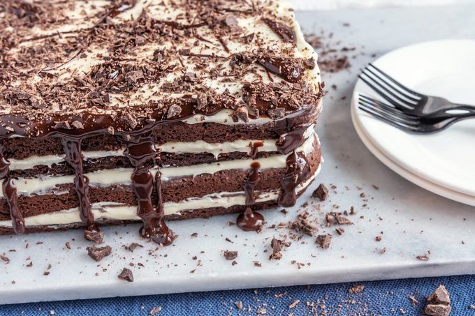 a cake with chocolate and cream frosting on a white plate next to a fork