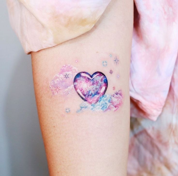 a small heart tattoo on the left side of the right arm, with clouds and stars around it