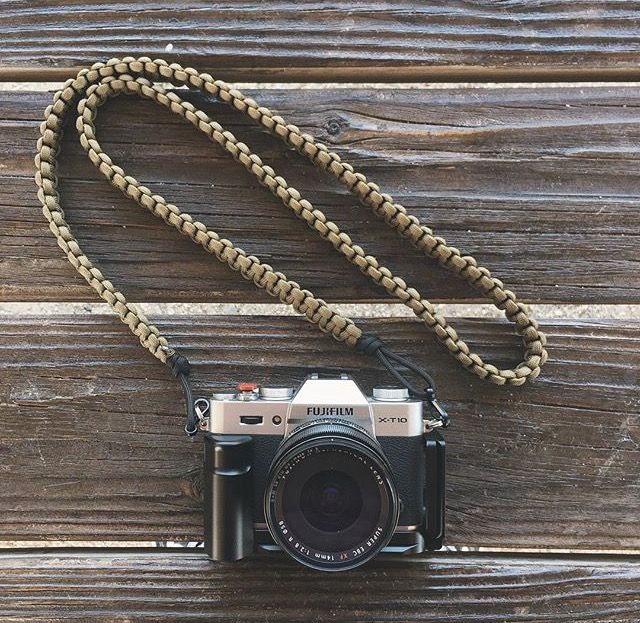 an old camera with a cord attached to it sitting on a wooden surface next to a chain