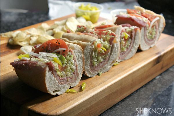 a wooden cutting board topped with sandwiches and chips