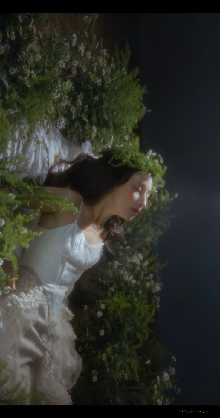 a woman in a white dress is surrounded by greenery