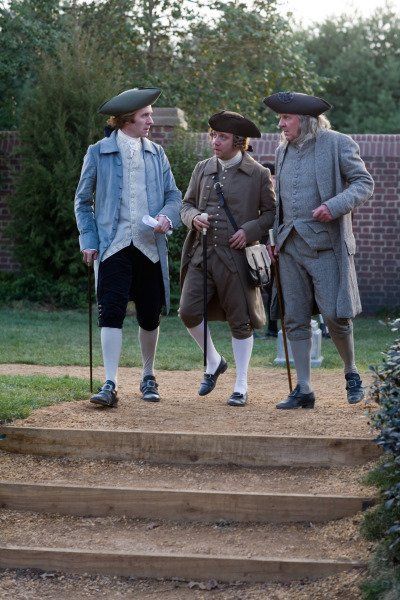 three people dressed in period clothing standing on steps