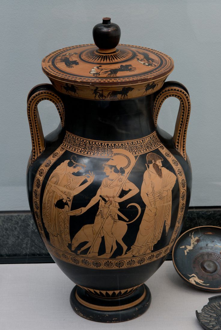 an old vase with two men on it and another bowl next to it, in front of a wall