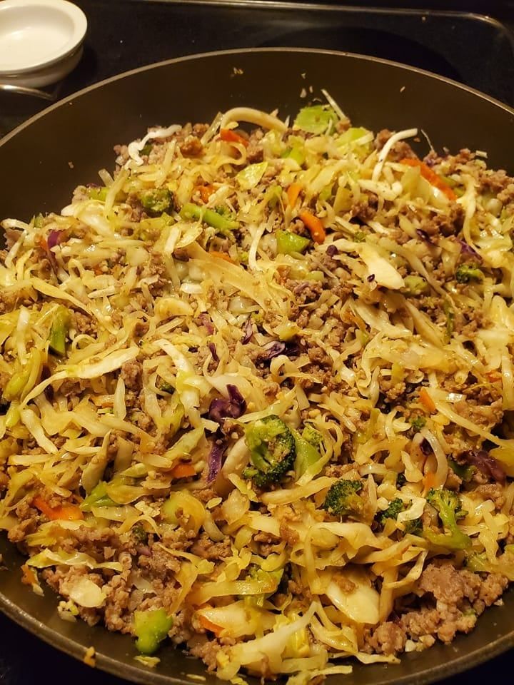 a wok filled with meat and vegetables on top of a stove burner,