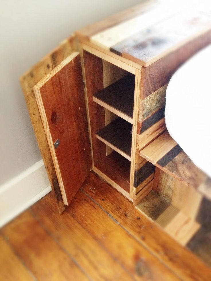 a wooden cabinet sitting on top of a hard wood floor next to a white sink