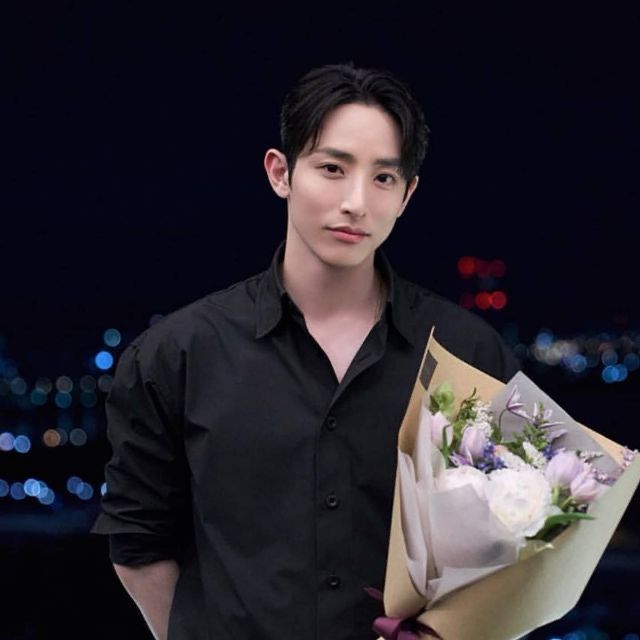 a man holding a bouquet of flowers in front of a cityscape at night