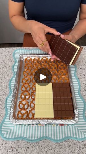 a woman holding a tray with chocolate and pretzels on it