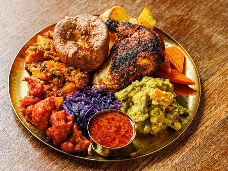 a plate filled with different types of food on top of a wooden table next to a bagel