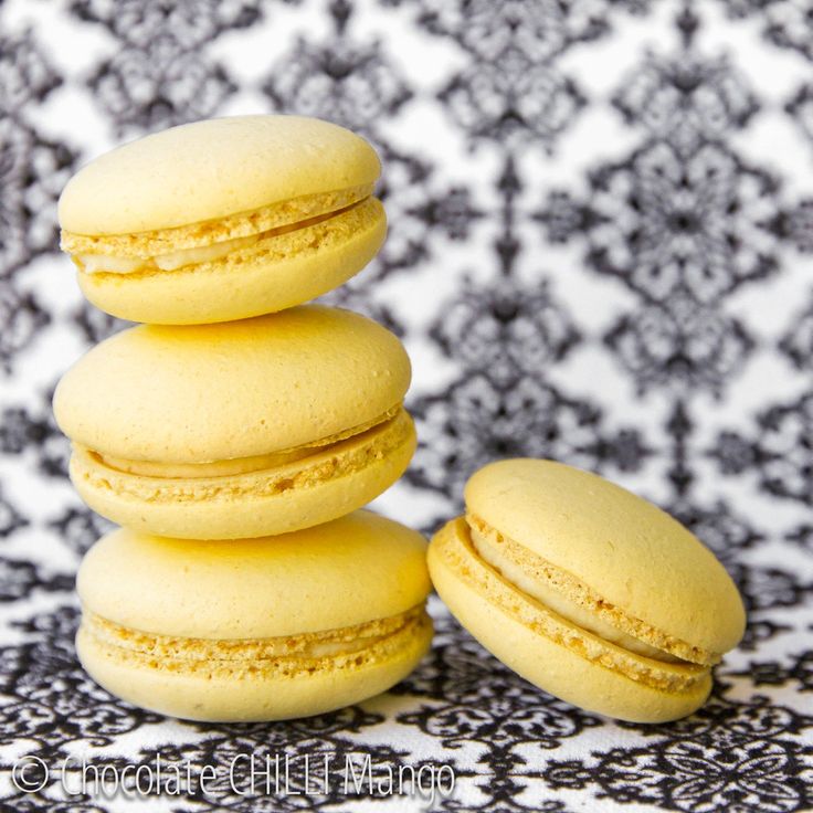 a stack of yellow macaroons sitting on top of a black and white table cloth