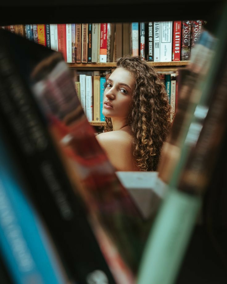 a woman sitting in front of bookshelves with her head turned to the side