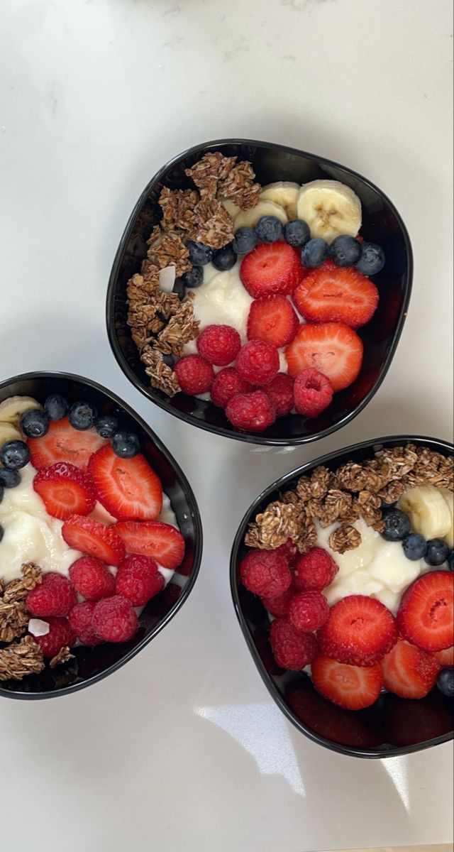 three black bowls filled with fruit and granola