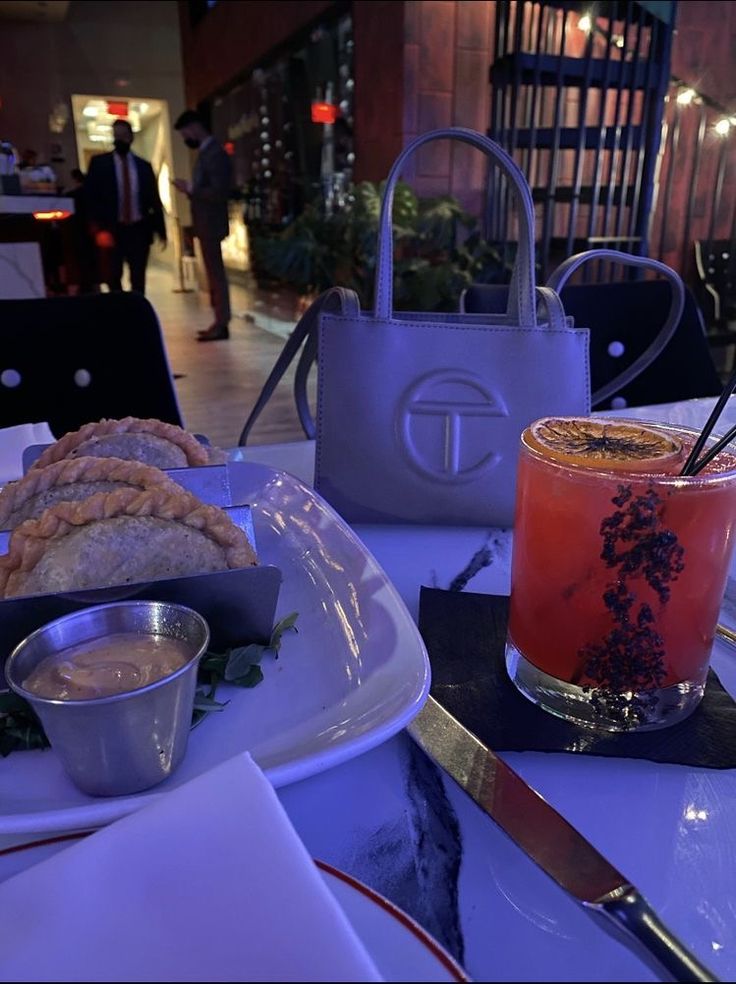 a table topped with plates and cups filled with food next to a handbag on top of a plate