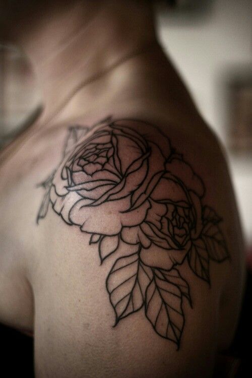 a black and white photo of a woman's shoulder with a rose tattoo on it