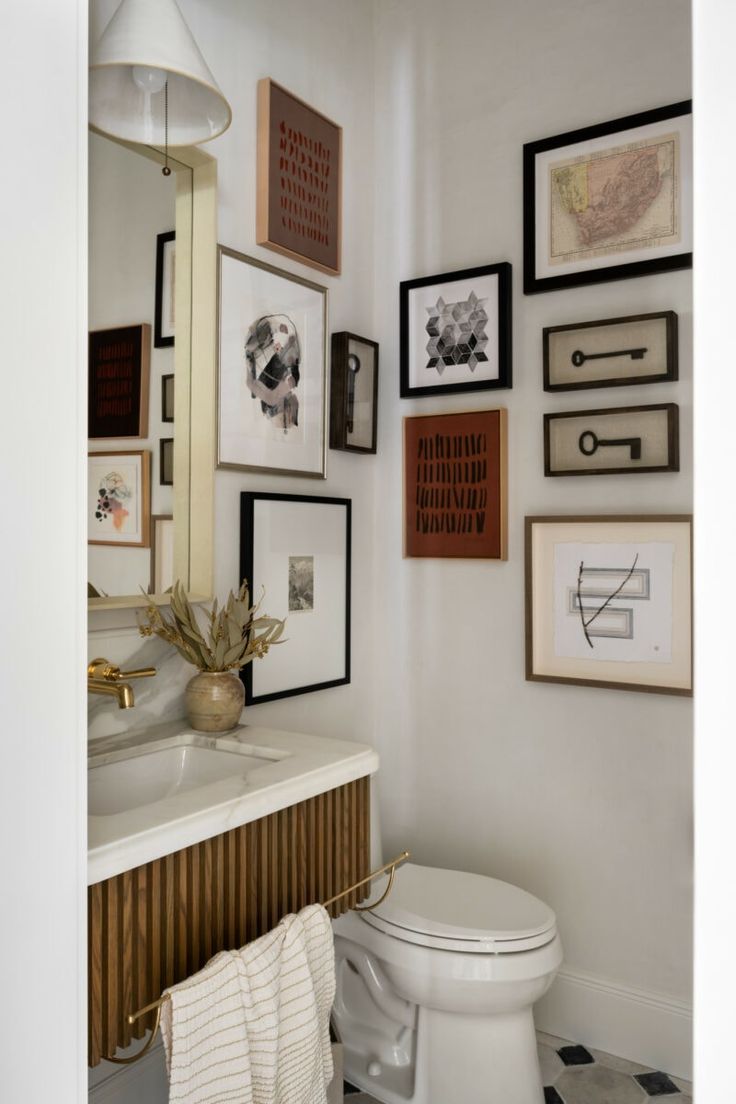 a white toilet sitting in a bathroom next to a wall with pictures on it's walls