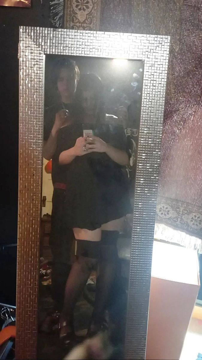 a woman taking a selfie in front of a mirror with her reflection on it