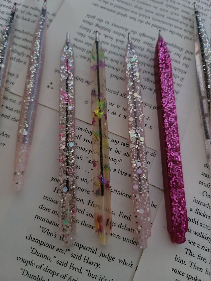 five glittered pencils sitting on top of an open book