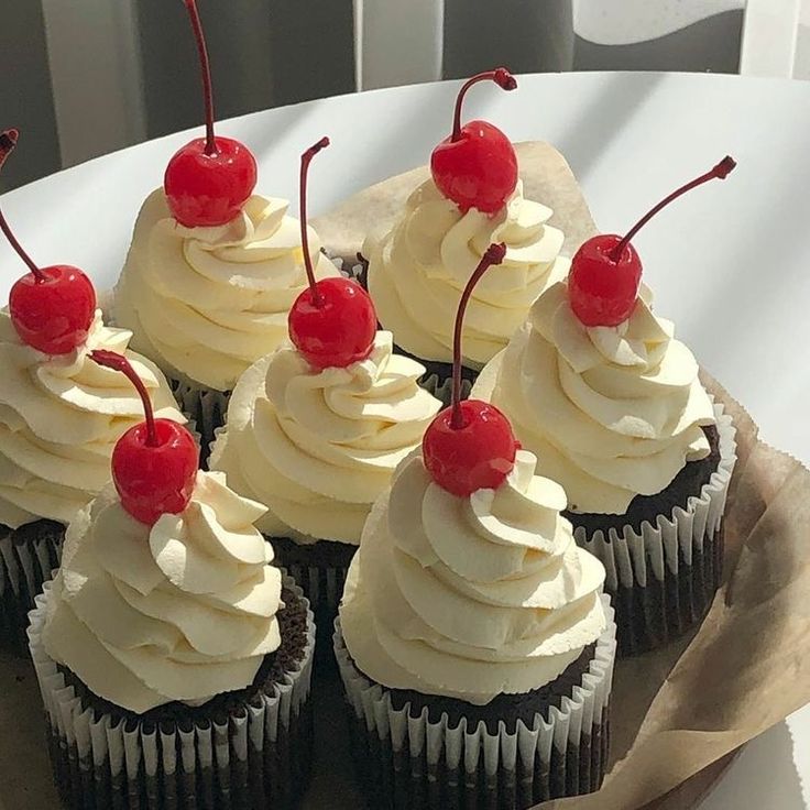 cupcakes with white frosting and cherries on top