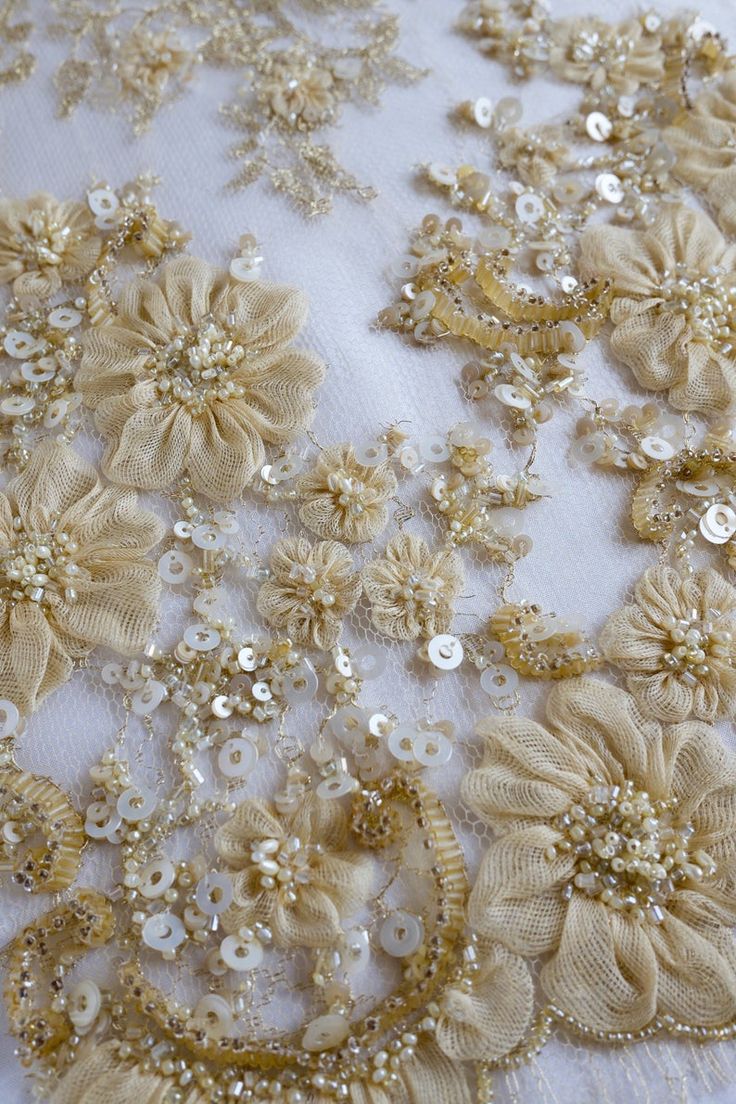 an embroidered fabric with gold flowers and pearls on the bottom, along with sequins