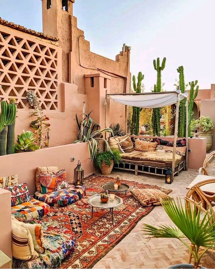 an outdoor living area with couches, rugs and cacti