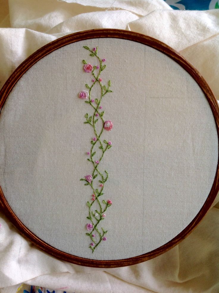 a cross stitched floral design on a white linen with brown frame and wood trim