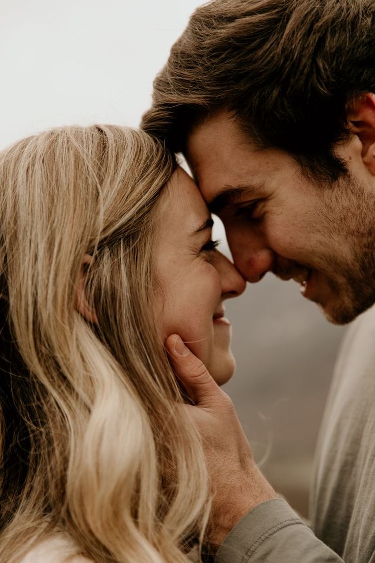 a man and woman are smiling at each other while they hold their foreheads close together