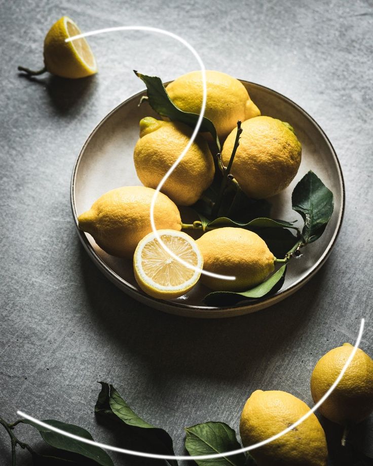 a bowl filled with lemons on top of a table