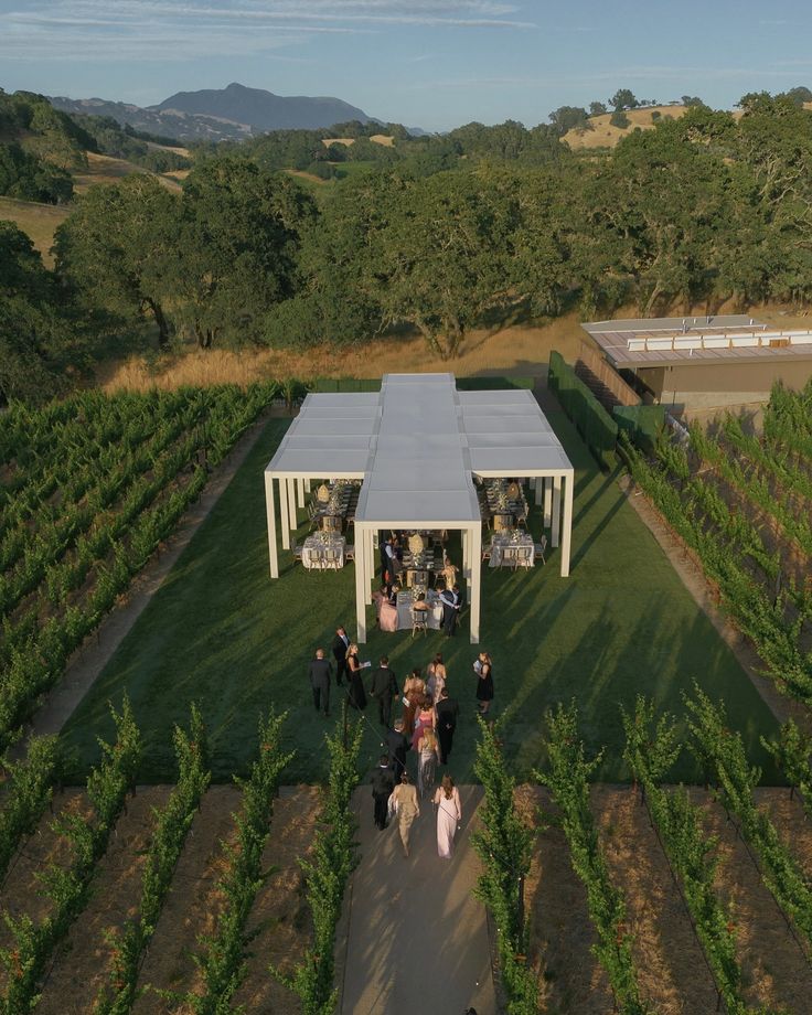 an aerial view of people standing in the middle of a field near a large white tent