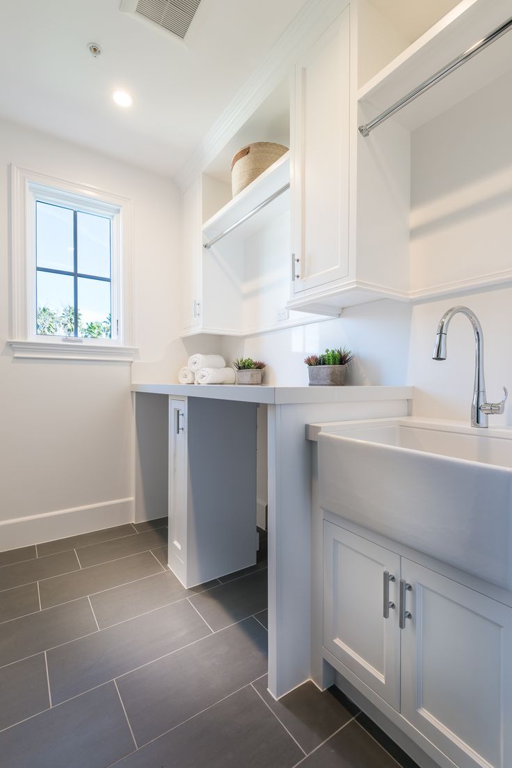 a white kitchen with gray tile flooring and counter tops, along with a window