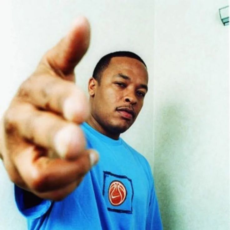 a man pointing at the camera with his hand in front of him and wearing a blue shirt