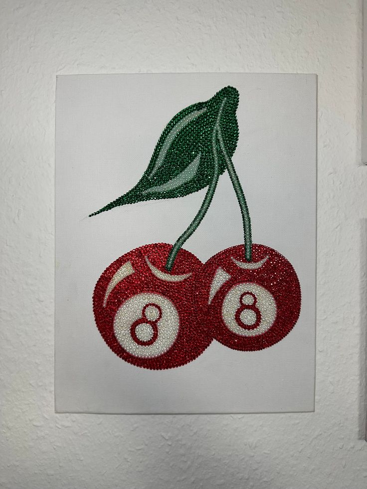 a piece of art with two cherries on it