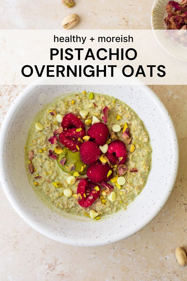 a white bowl filled with oatmeal topped with raspberries and pistachio