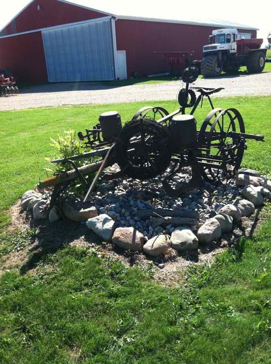 an old fashioned bike sitting in the middle of a field next to a fire pit