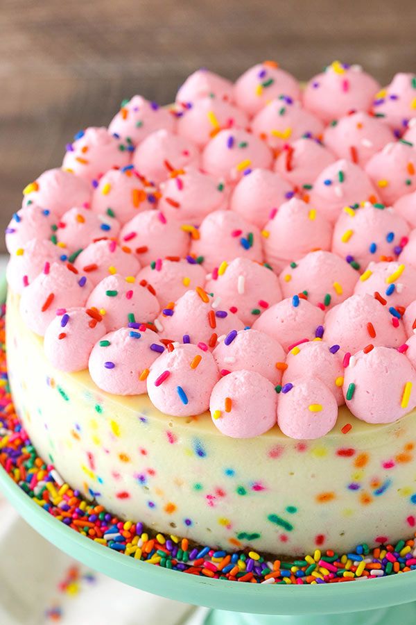 a cake with pink frosting and sprinkles on top sitting on a plate