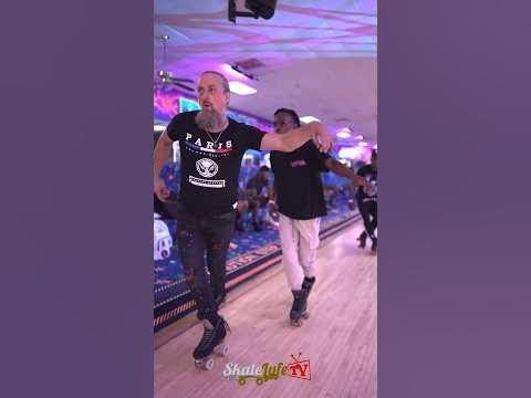 a man in black shirt and white pants rollerblading down a bowling alley with other people