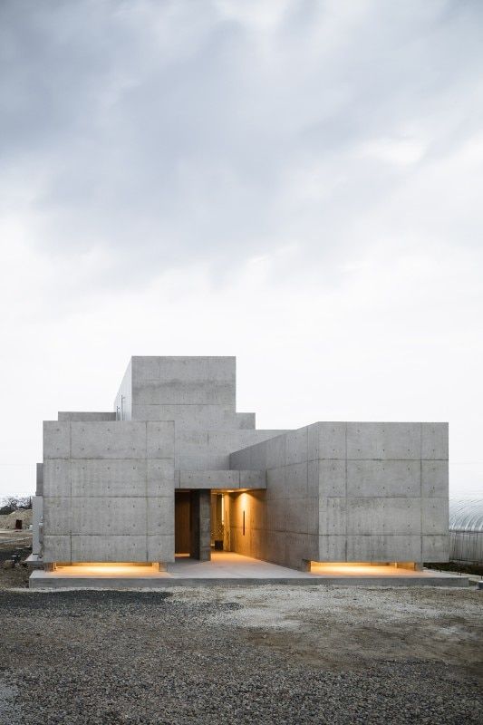 a concrete building with two lights on the outside and one door open to let in light