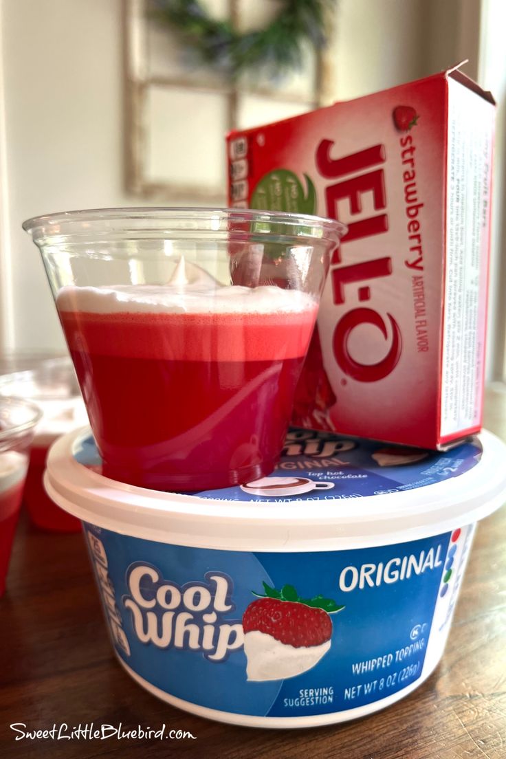 an ice cream container with a strawberry drink in it and a carton of jello next to it