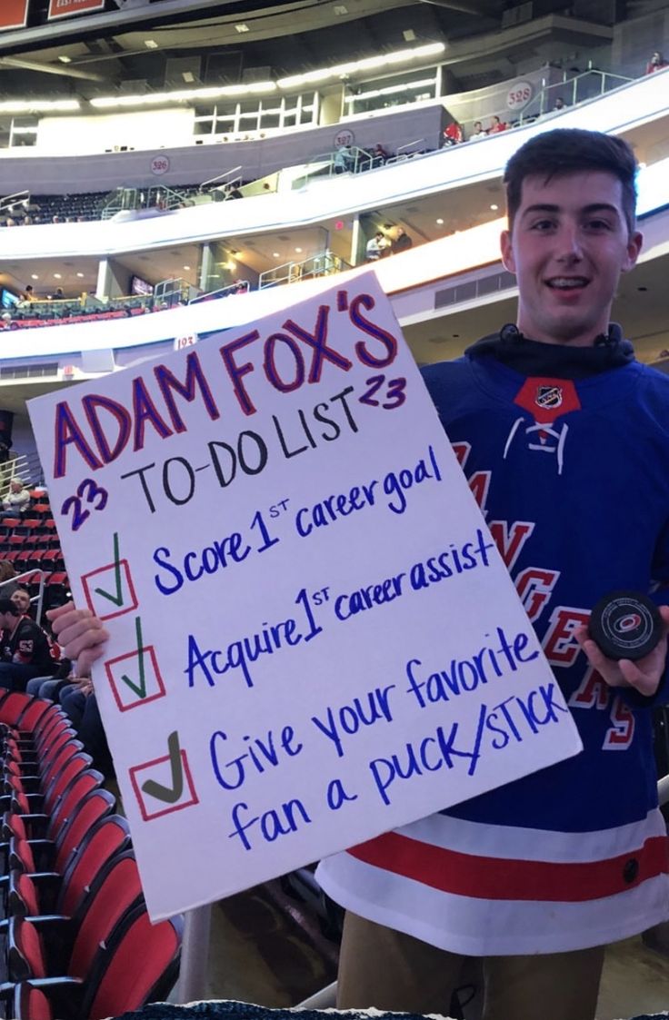 a man holding up a sign in front of an empty stadium bleachers filled with fans