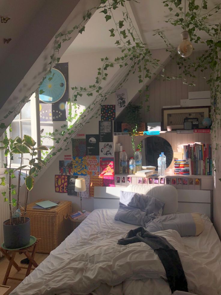 an attic bedroom with plants growing on the wall and bed in the foreground, under a slanted ceiling