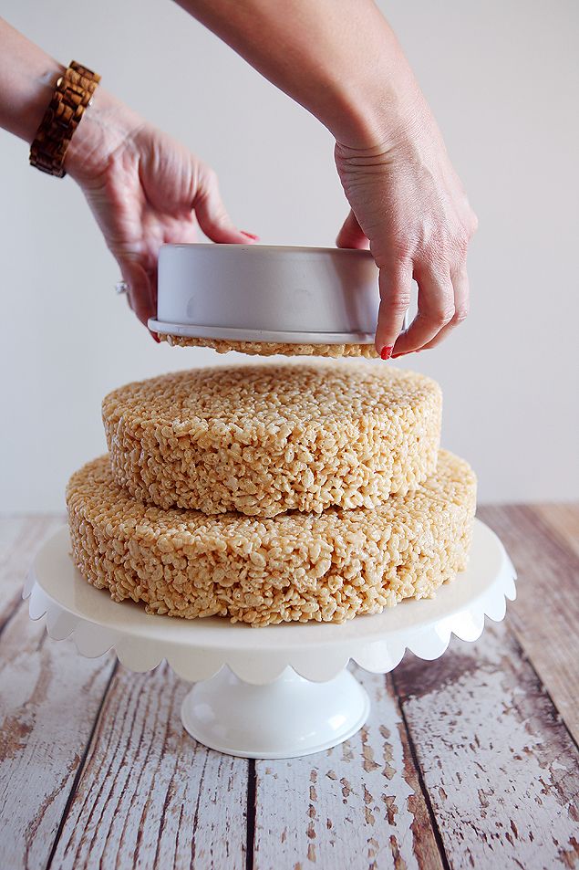 a person using a knife to cut a cake on top of a wooden table with white frosting