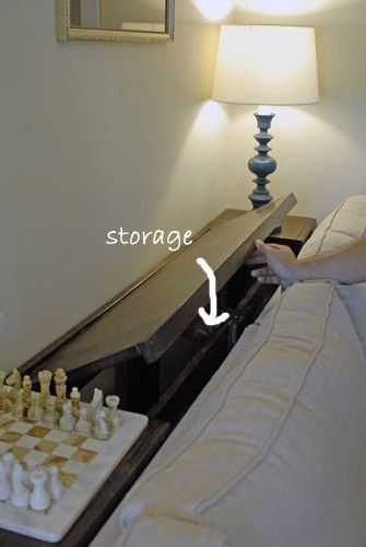 a bed with a chess board on it next to a night stand and lamp in the corner